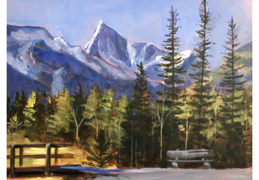 Purple mountains in the background compliment pine and other trees in the middle area. Three is a bridge on the left and a bench on the right in the foreground.